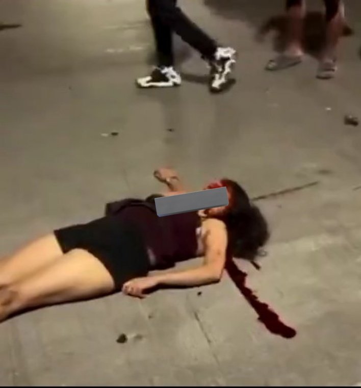 Woman lying injured on a road with blood beside her head after an accident, face blurred