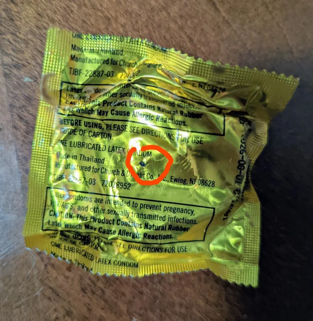 Condom wrapper with a tiny pinhole circled in red