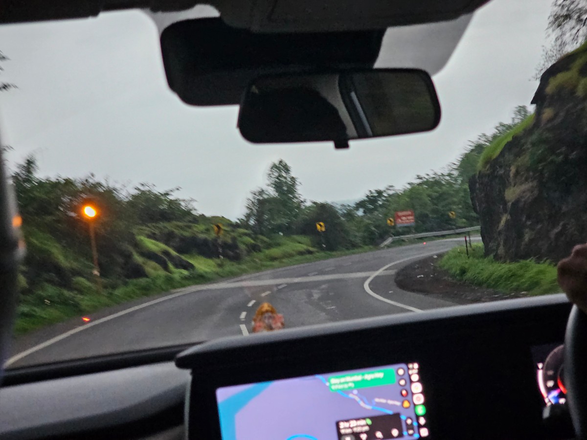 View through a car windscreen of a winding road through green hills